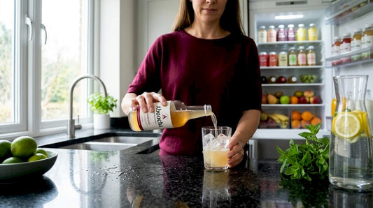 Woman pouring kombucha into glass in kitchen