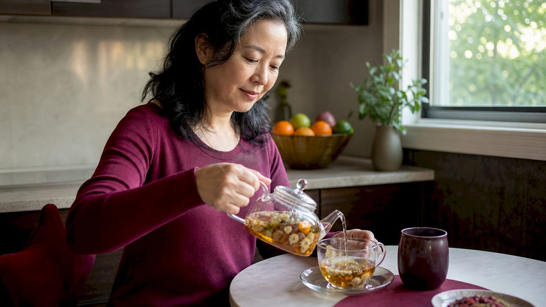Woman pouring botanical tea in bright kitchen