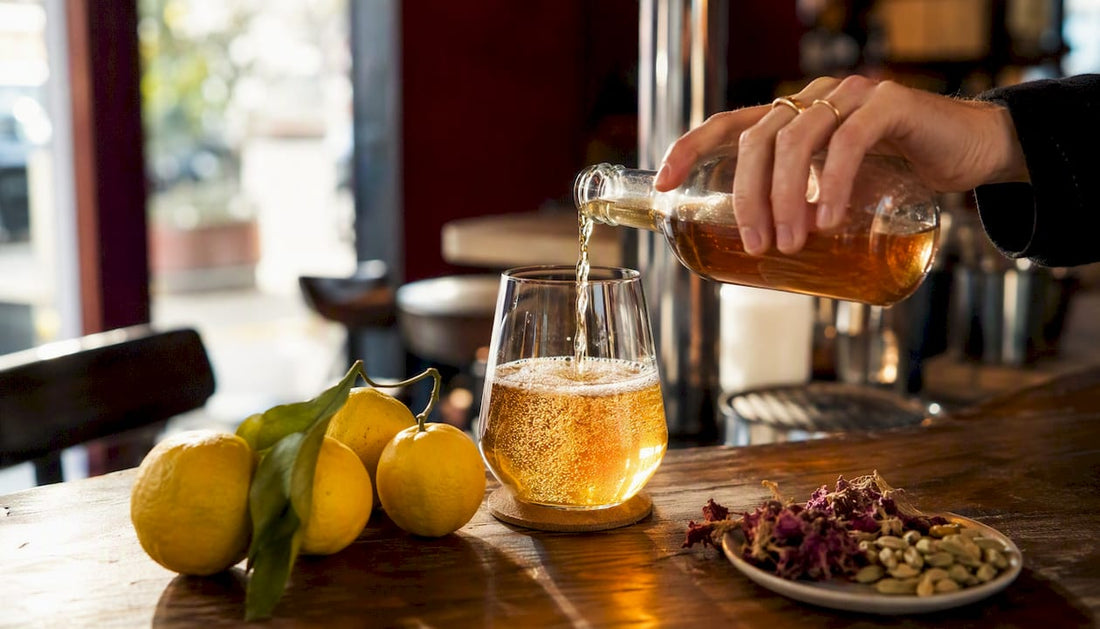 Hand pouring kombucha into glass in kitchen