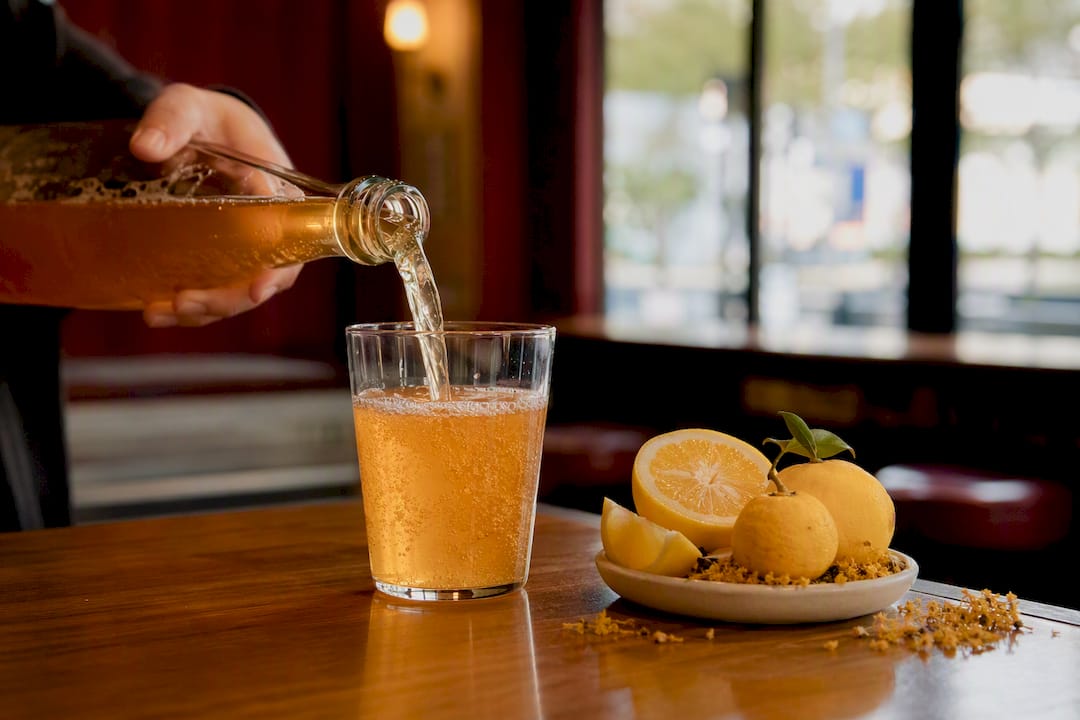Hand pouring kombucha into glass tumbler