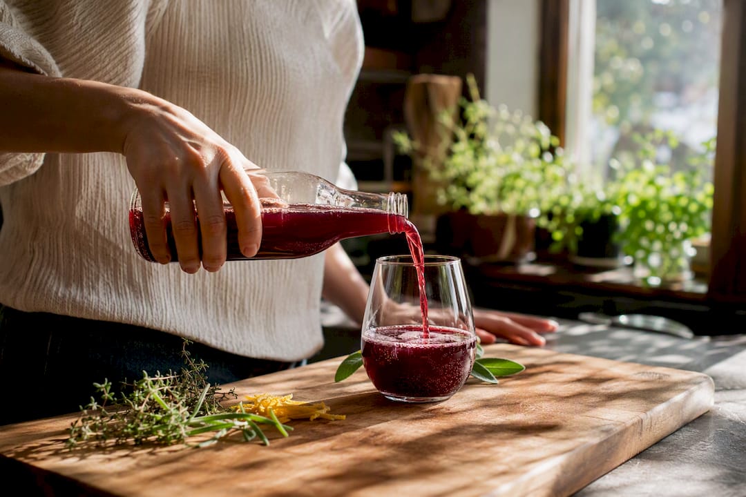 Pouring burgundy kombucha into glass